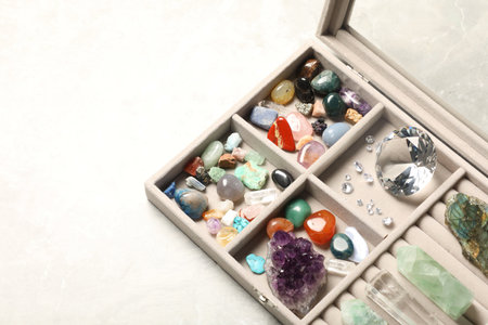 Box with beautiful gemstones on light table, closeup. Space for textの写真素材