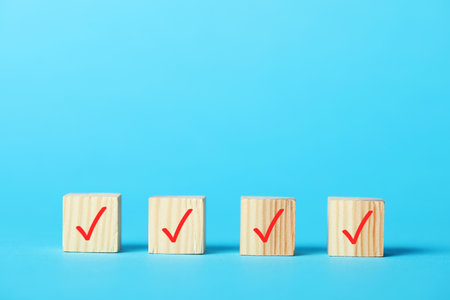 Wooden cubes with check marks on light blue backgroundの写真素材