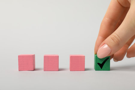 Woman taking green cube with check mark on white background, closeupの写真素材