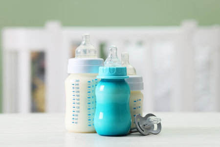 Feeding bottles with milk and pacifier on white wooden table indoorsの写真素材