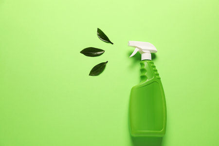 Spray bottle of cleaning product and leaves on green background, flat lay. Space for textの写真素材