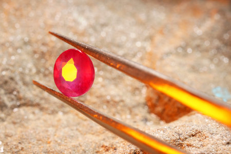 Tweezers with beautiful pink gemstone on stone, closeup