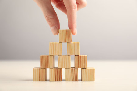 Woman building pyramid of wooden cubes at table, closeupの写真素材