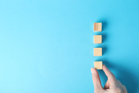 Wooden cubes on light blue background, top view. Space for textの写真素材