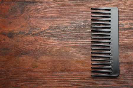 One black plastic comb on wooden background, top view. Space for textの写真素材