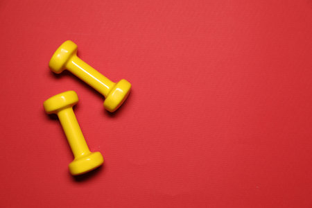 Dumbbells on red background, flat lay. Space for textの写真素材