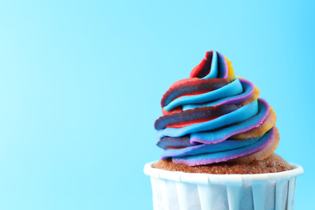 One delicious cupcake with colorful cream on light blue background, closeup. Space for textの写真素材