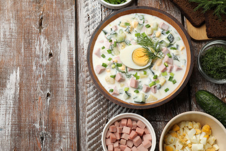 Okroshka soup with kefir in bowl and ingredients on wooden table, flat lay. Space for textの写真素材