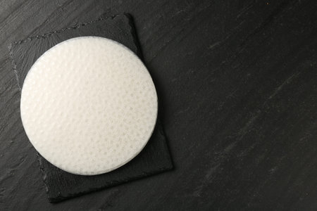Stack of rice paper sheets on dark textured table, top view. Space for text