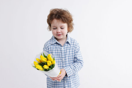Cute little boy with bouquet of tulips on white background