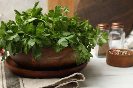 Fresh parsley in bowl and spices on white table, closeupの写真素材