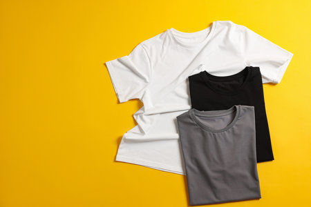 Blank t-shirts on yellow background, flat lay. Mockup for designの写真素材