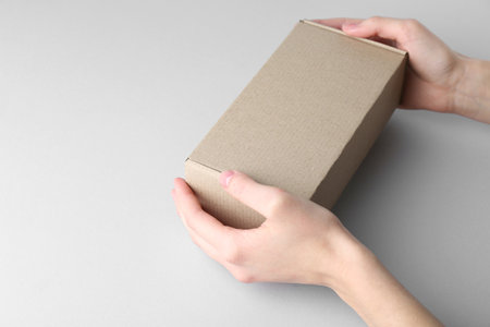 Woman with blank cardboard box on white background, closeup. Mockup for designの写真素材