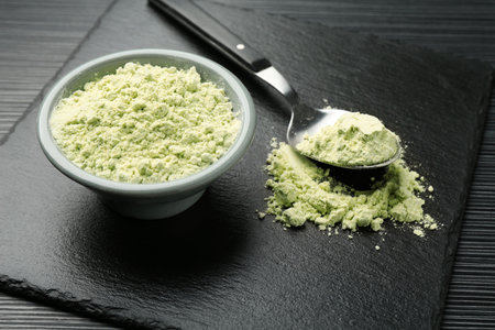 Dry wasabi powder and spoon on black textured table, closeupの写真素材