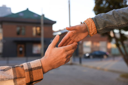 Man offering helping hand to his friend on city street, closeup