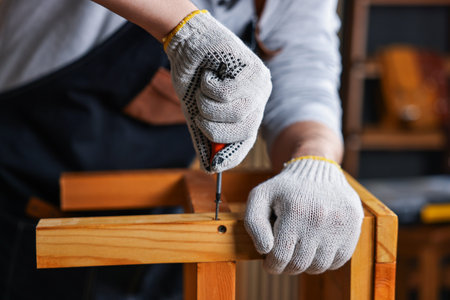 Carpenter repairing wooden stool in workshop, closeupの写真素材