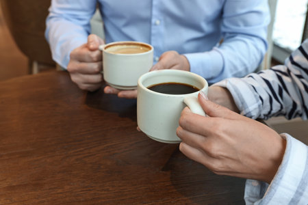Colleagues having coffee break at wooden table in cafe, closeupの写真素材