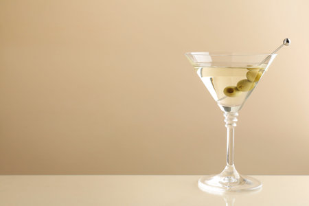 Martini cocktail with olives in glass on beige table, space for textの写真素材