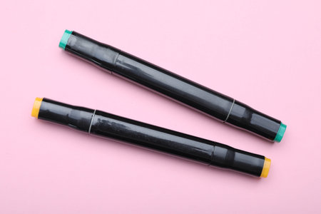 Two color markers on pink background, top view