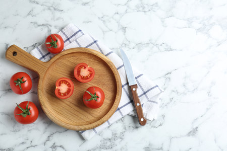 Wooden cutting board, tomatoes and knife on white marble table, flat lay. Space for textの写真素材