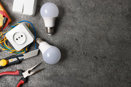 Different electrical tools on grey table, flat lay. Space for text