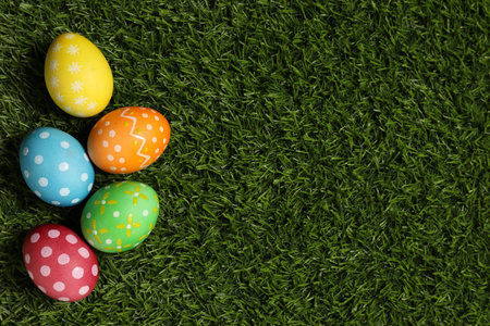 Beautiful decorated Easter eggs on green grass, flat lay. Space for textの写真素材