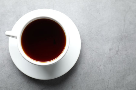 Refreshing black tea in cup on grey textured table, top view. Space for textの写真素材