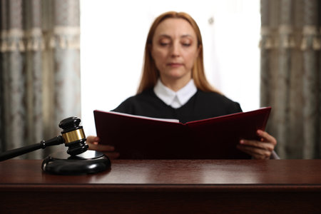 Judge with folder of documents at wooden table in courtroom, focus on gavelの写真素材