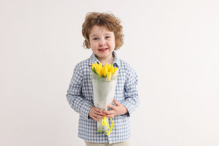 Cute little boy with bouquet of tulips on white background