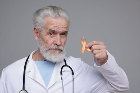 Multiple Sclerosis awareness. Doctor with orange ribbon on gray backgroundの写真素材