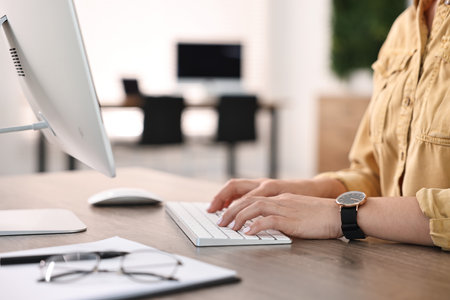 Woman working on computer at table in office, closeupの写真素材