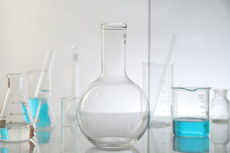 Laboratory glassware on mirror surface against light backgroundの写真素材