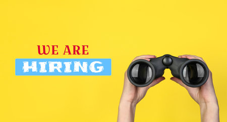 Woman holding binoculars on yellow background, closeup. Banner design. Human resource, recruitment conceptの写真素材