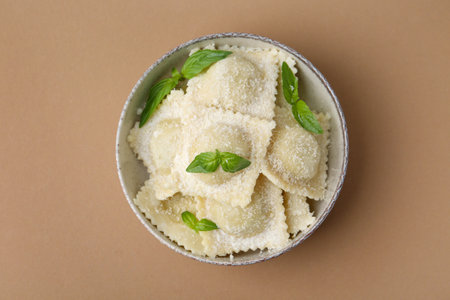 Delicious ravioli with cheese and basil on brown background, top viewの写真素材