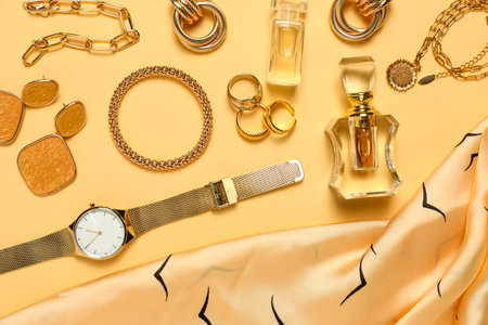 Many stylish jewelry, perfume and accessories on pale yellow background, flat lay