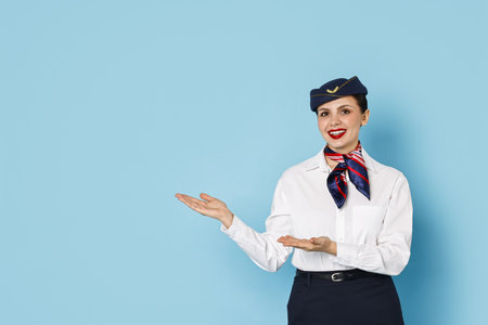 Happy flight attendant showing something on light blue background.の写真素材