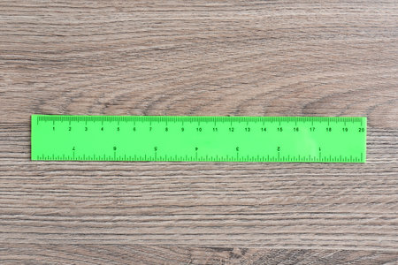 One green ruler on wooden table, top viewの写真素材