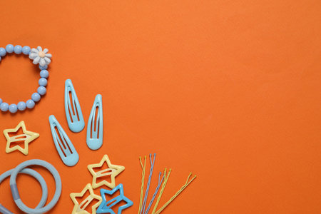 Cute hair accessories on orange background, flat lay. Space for text