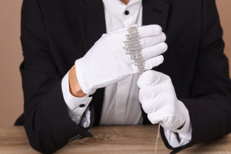 Appraiser in gloves with luxury necklace at wooden table, closeupの写真素材