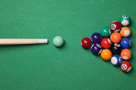 Billiard balls in triangle and cue on green table, top viewの写真素材