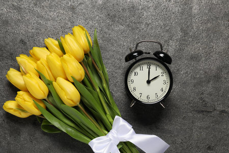 Spring time. Alarm clock and beautiful tulips on gray table, flat layの写真素材