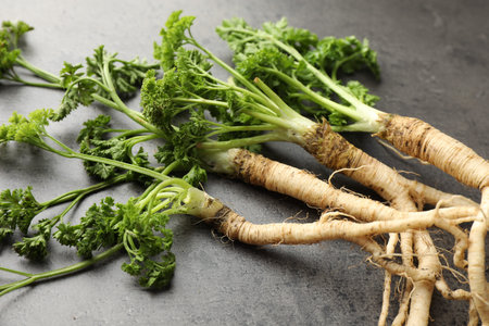 Parsley roots with leaves on black table, closeup