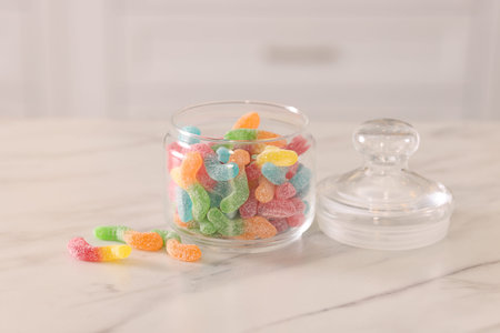 Gummy candies in glass jar on white marble table indoors