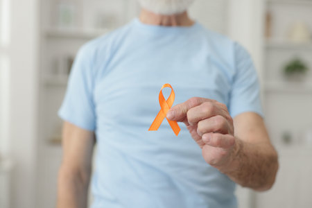 Multiple Sclerosis awareness. Senior man with orange ribbon indoors, closeup
