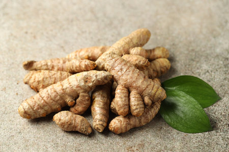 Pile of tumeric rhizomes with leaves on grey table, closeupの写真素材