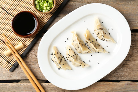 Delicious gyoza dumplings with sesame seeds served on wooden table, top viewの写真素材