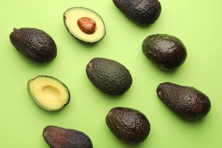 Fresh ripe avocados on light green background, flat lay
