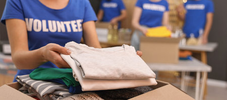 Volunteer putting clothes into donation box indoors, closeupの写真素材
