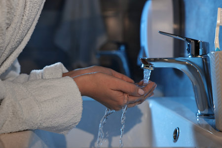 Woman washing her face over sink in bathroom, closeup