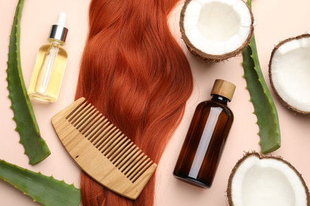 Cosmetic products, hair lock, coconut and aloe leaves on beige background, flat layの写真素材